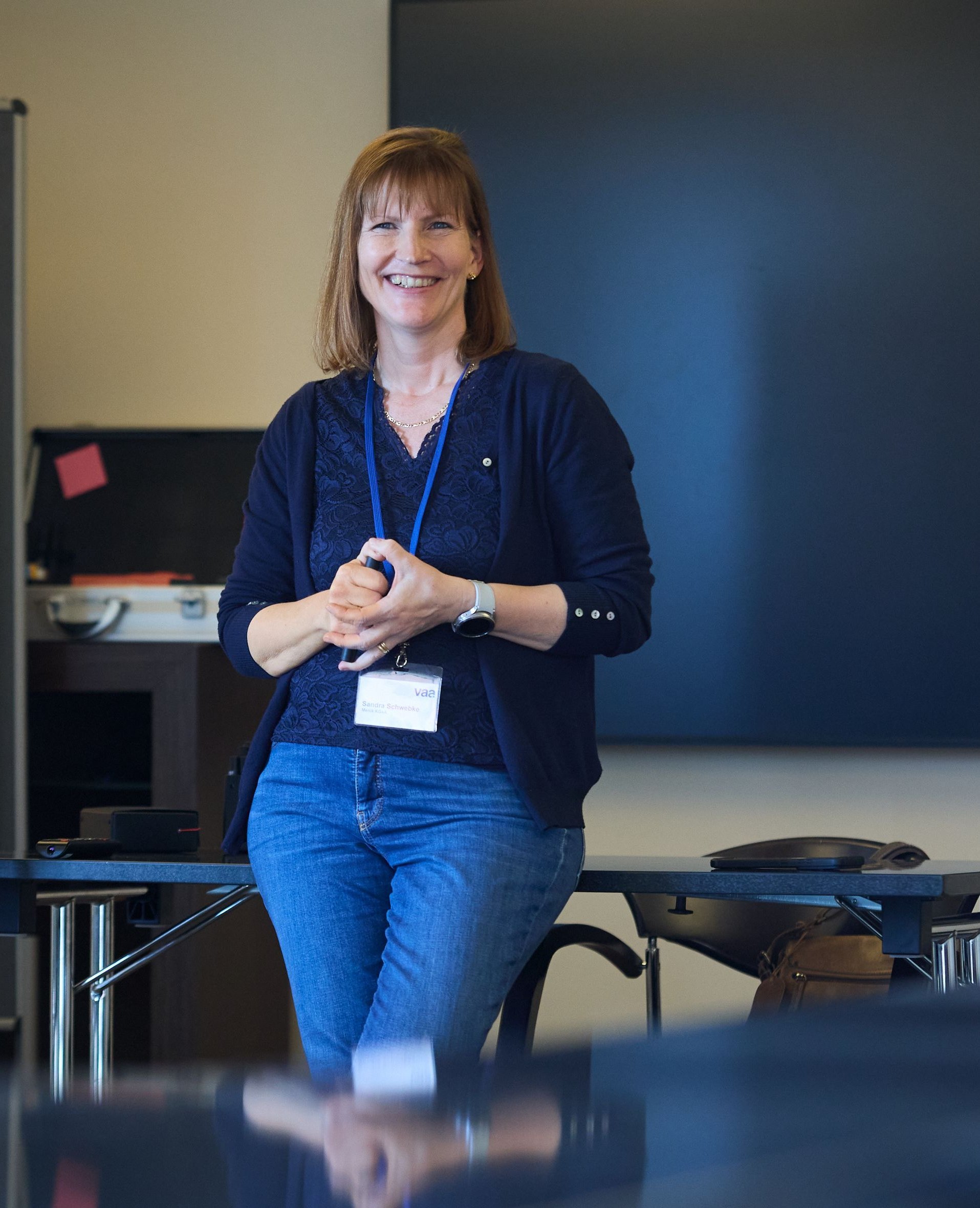 Sandra Schwebke steht an einen Tisch gelehnt vor einem Flipchart.