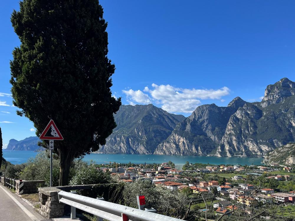 Blick von oben auf einen italienischen See in den Bergen, aufgenommen von der Straße, die zum malerischen Urlaubsort führt.