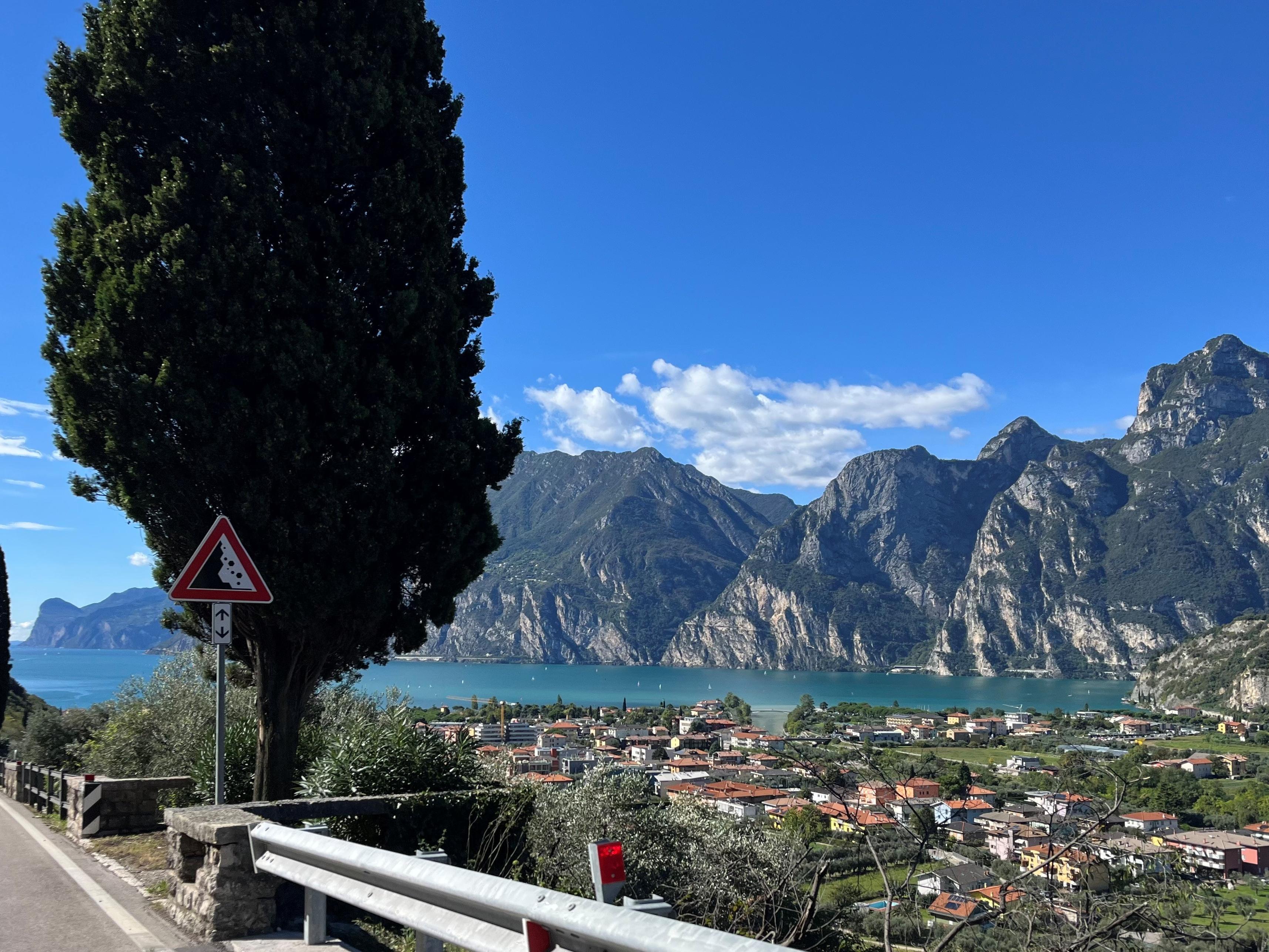 Blick von oben auf einen italienischen See in den Bergen, aufgenommen von der Straße, die zum malerischen Urlaubsort führt.