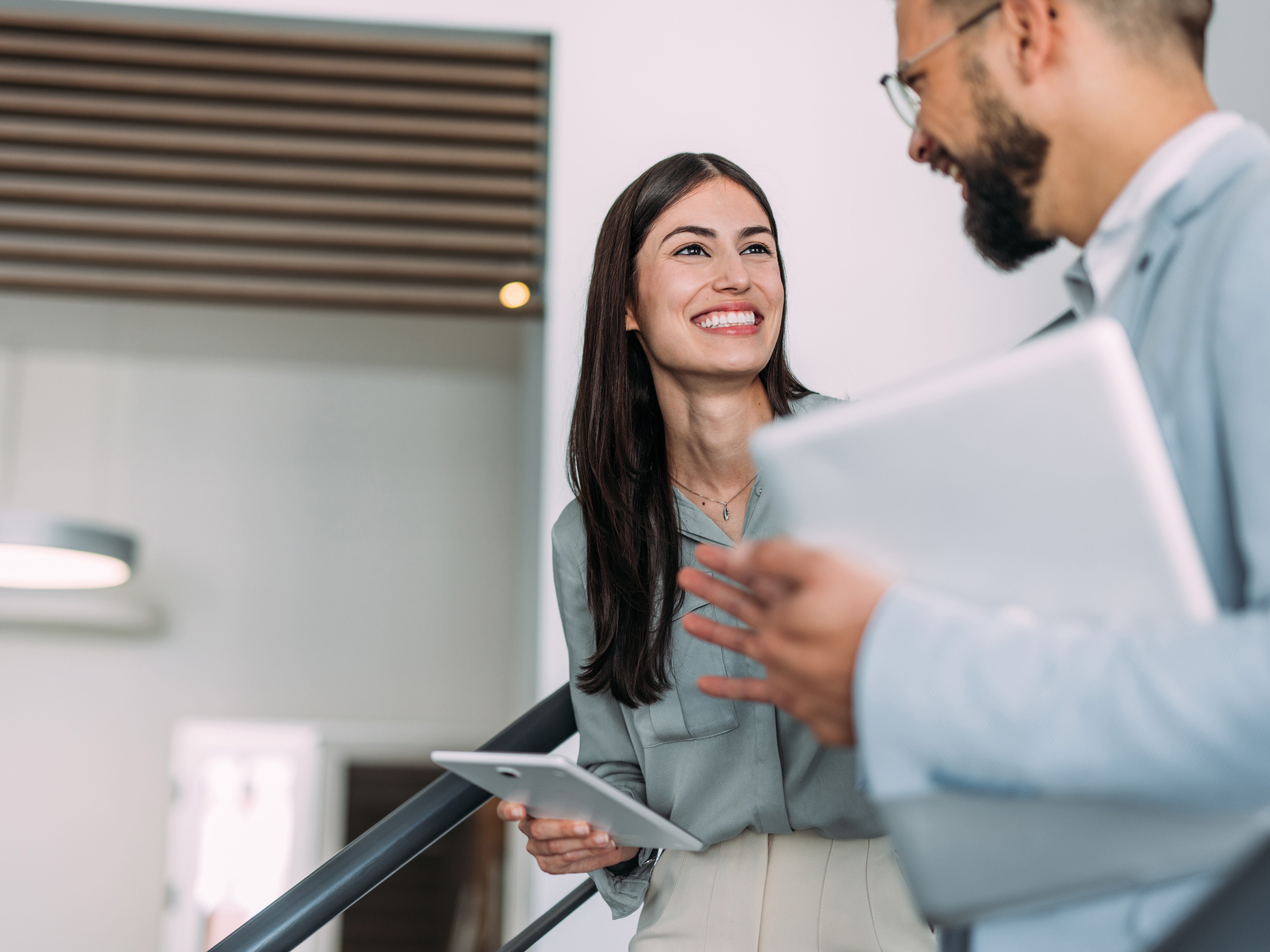 Junge Frau und junger Mann lachend im Büro.