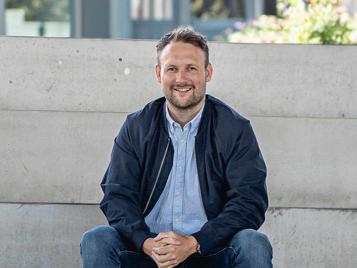 Stefan Weber sitzt entspannt auf Stufen und schaut freundlich in die Kamera.