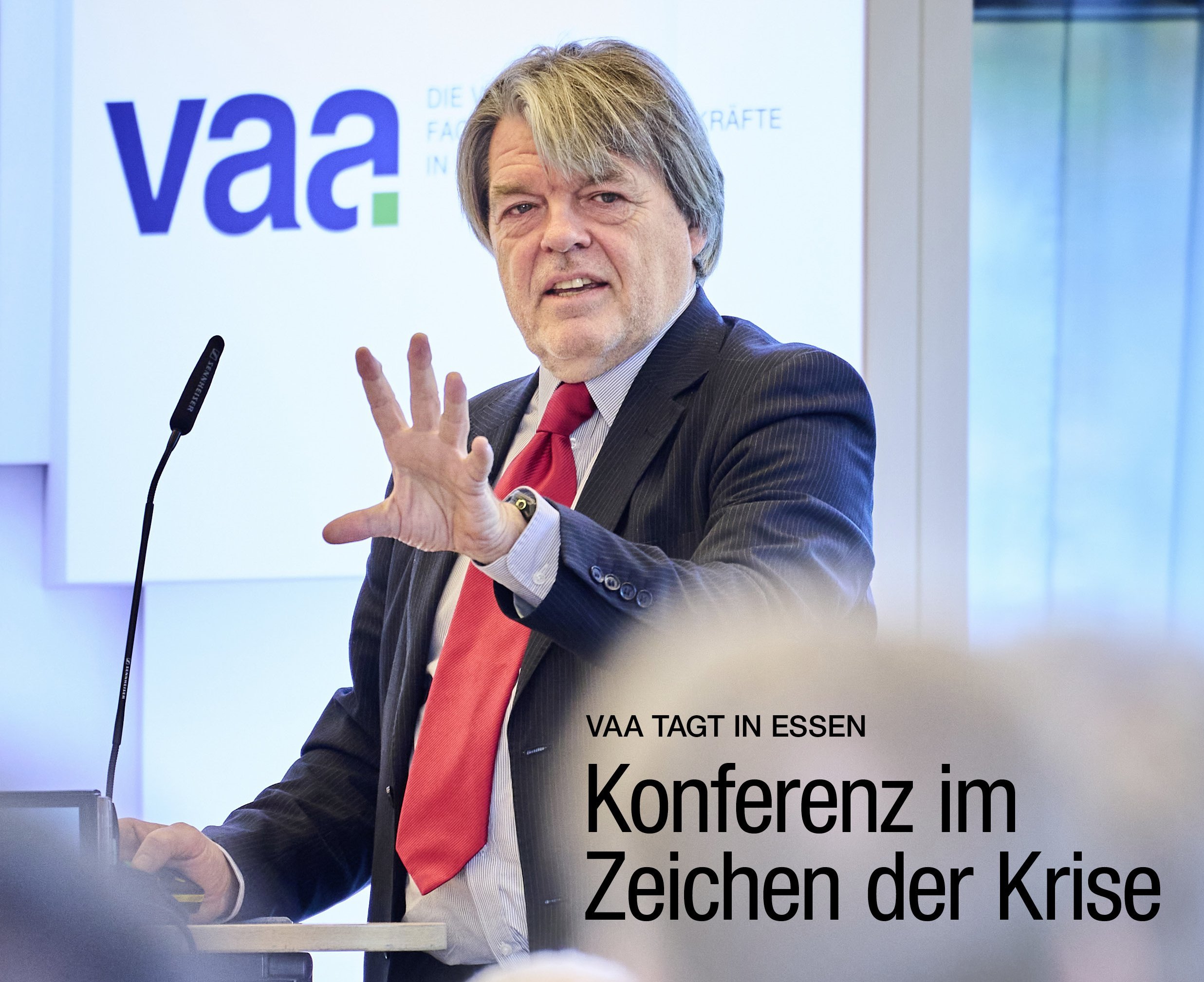 Cover des VAA Magazins, Ausgabe Dezember 2025: Das Coverfoto zeigt Denis Hicks bei der VAA-Jahreskonferenz. Mitte rechts die Headline: „Konferenz im Zeichen der Krise“.