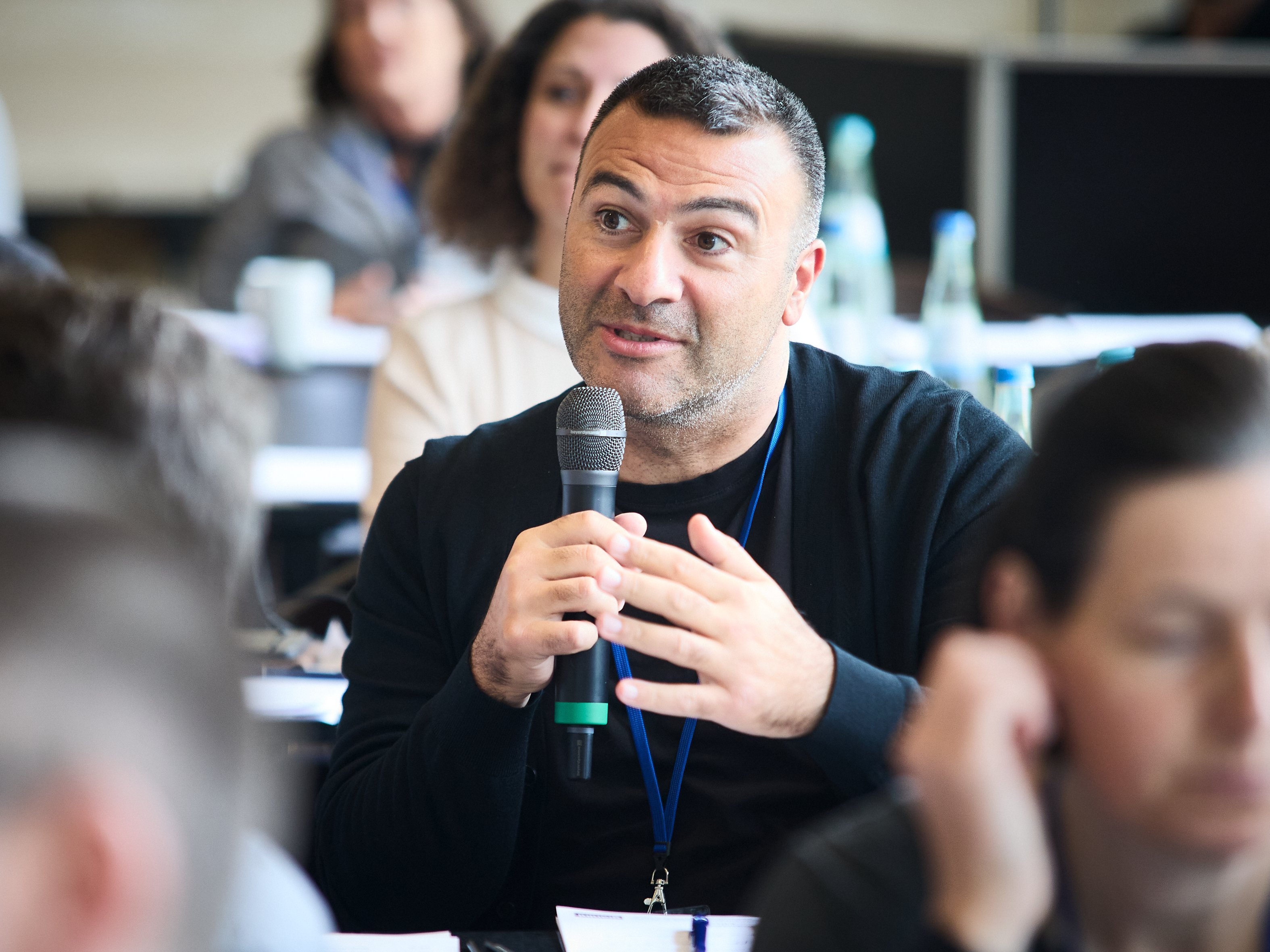 Roche-Betriebsratsmitglied Yasin Güler im Plenum in ein Mikro sprechend.