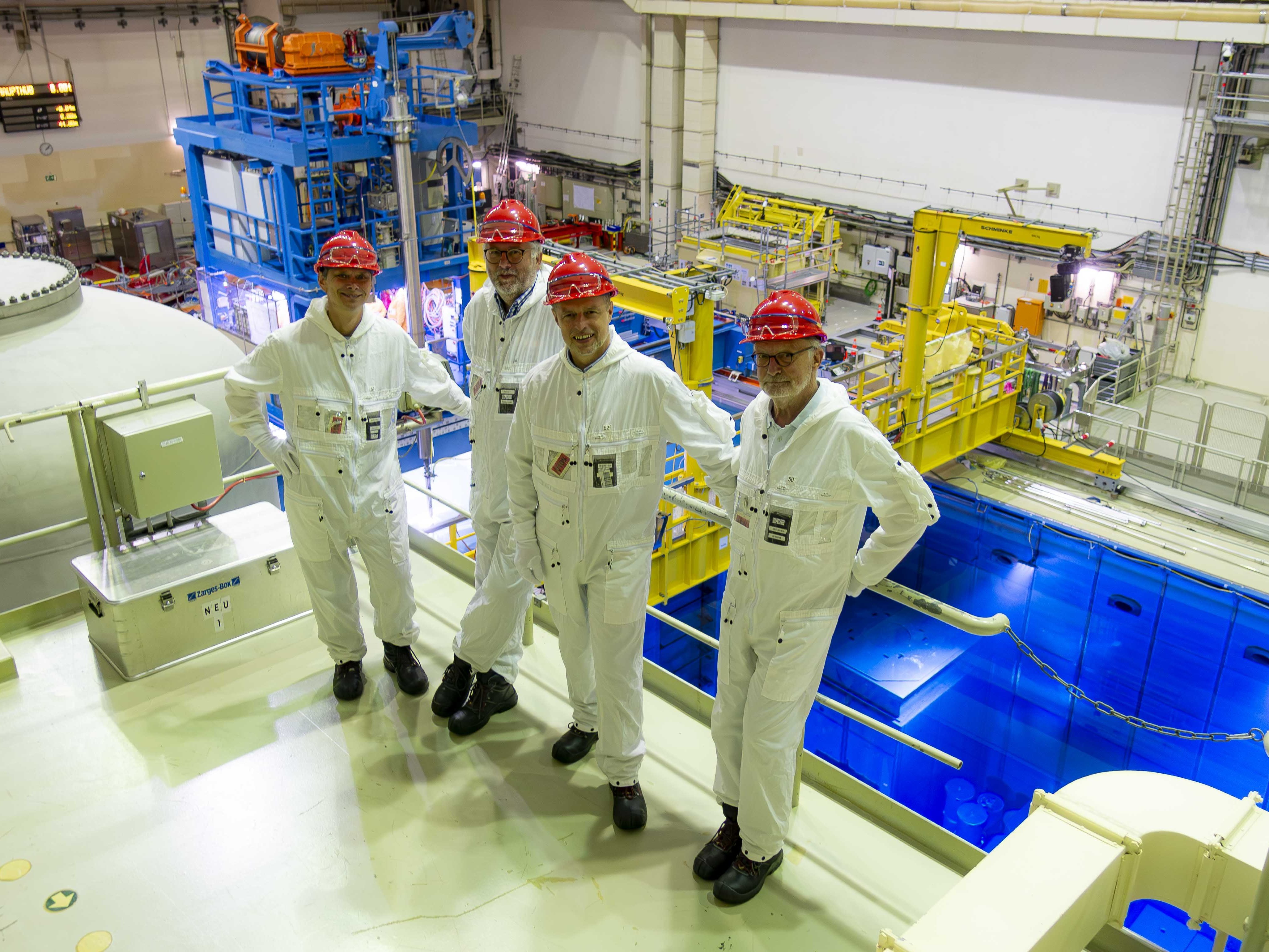 Eine Gruppe von vier Männern in weißen Arbeitsanzügen und rotem Helm im stillgelegten Kernkraftwerk Krümmel in Geesthacht.
