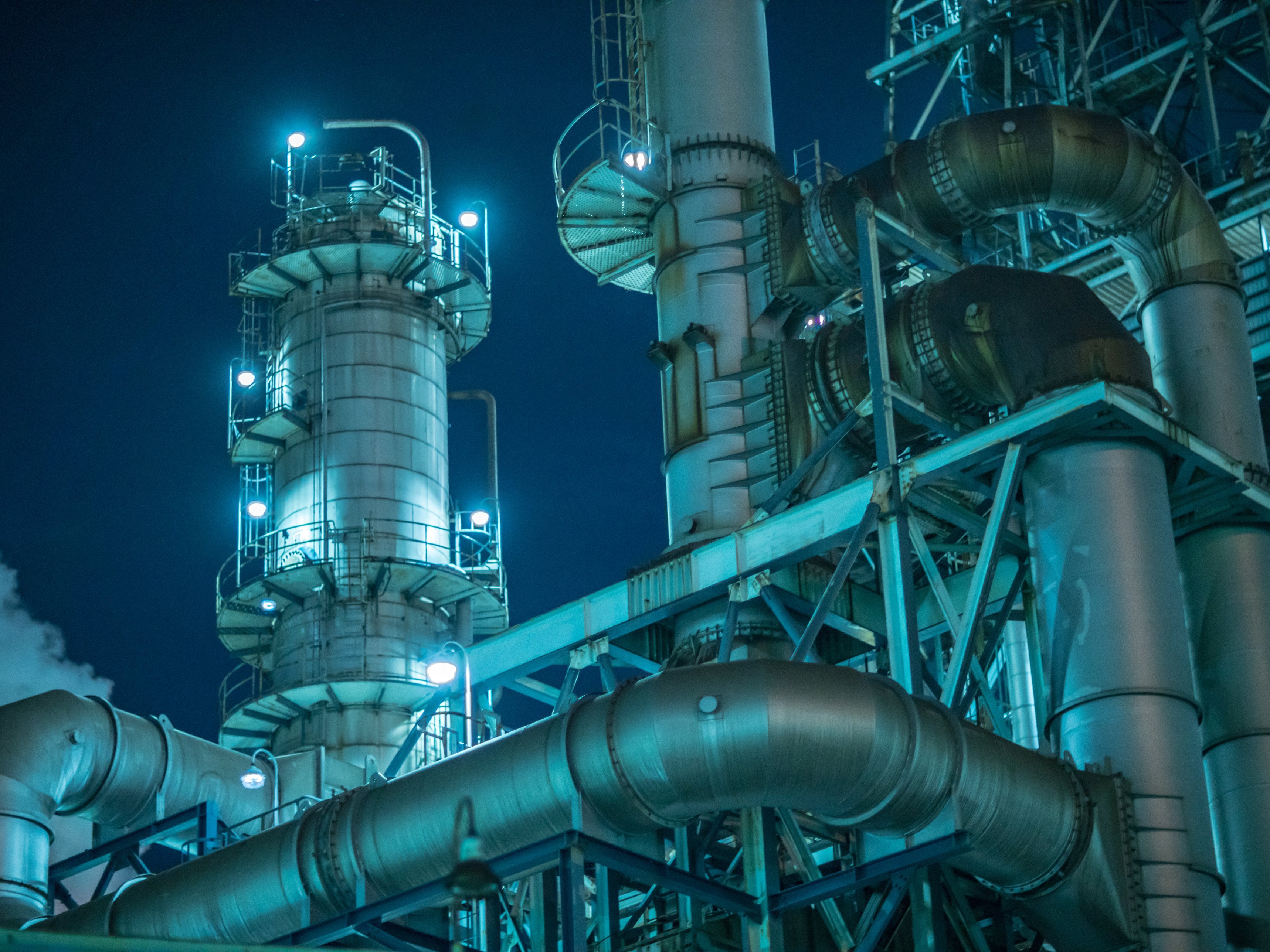 Eine beleuchtete Fabrik vor dunklem Nachthimmel.
