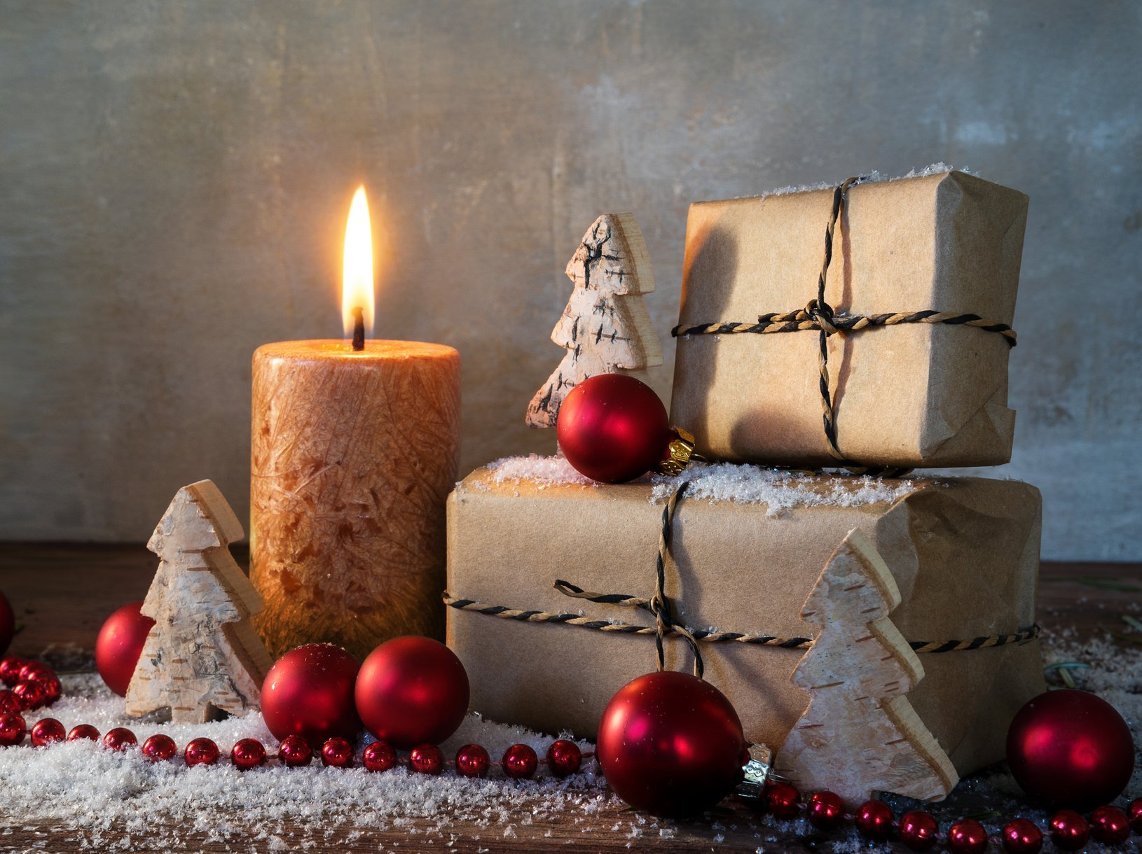 Weihnachtskerze vor Weihnachtsgeschenken