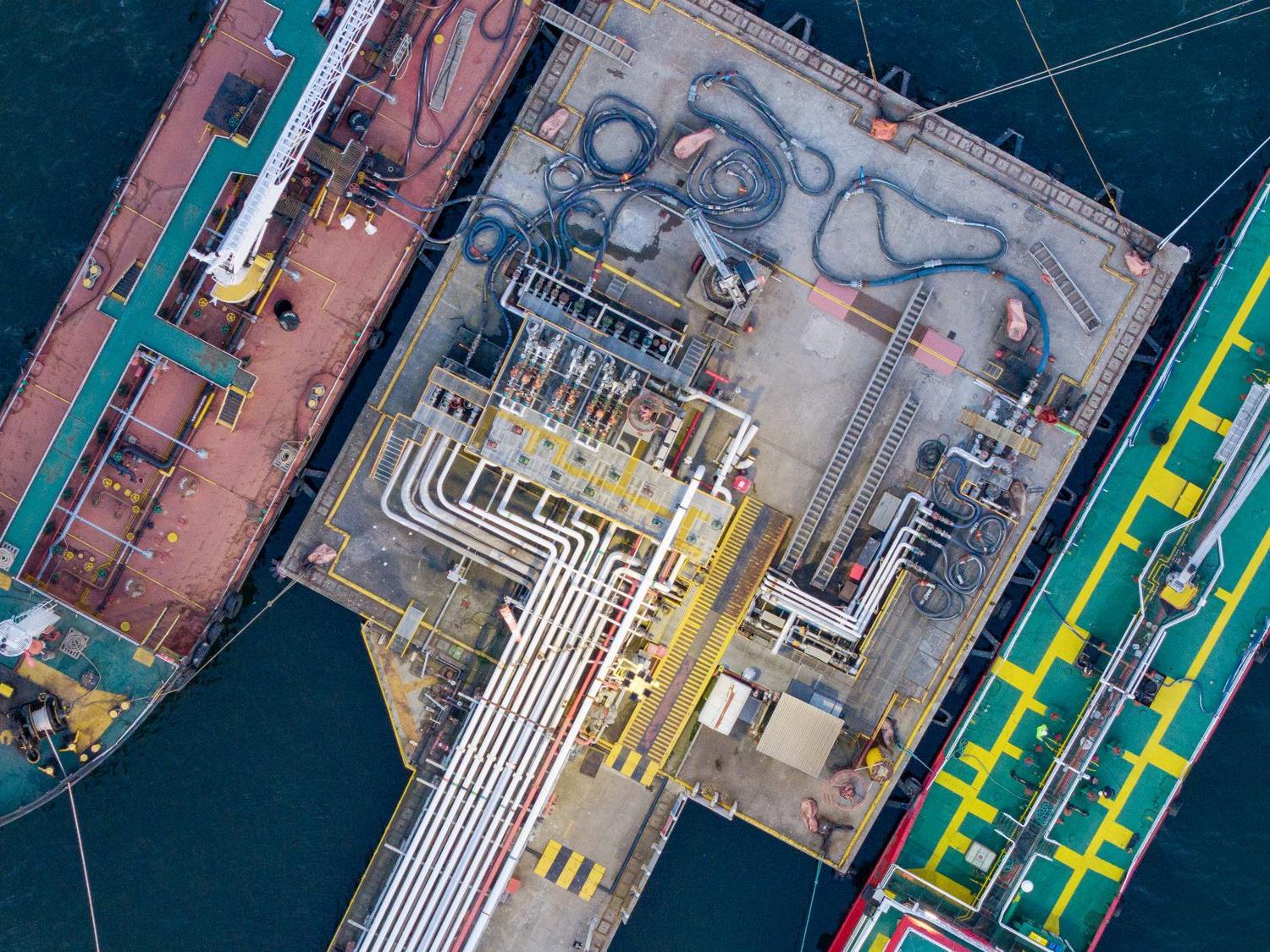 Luftaufnahme einer Verladeanlage mit Tankschiffen und Rohrleitungen im Hafen.