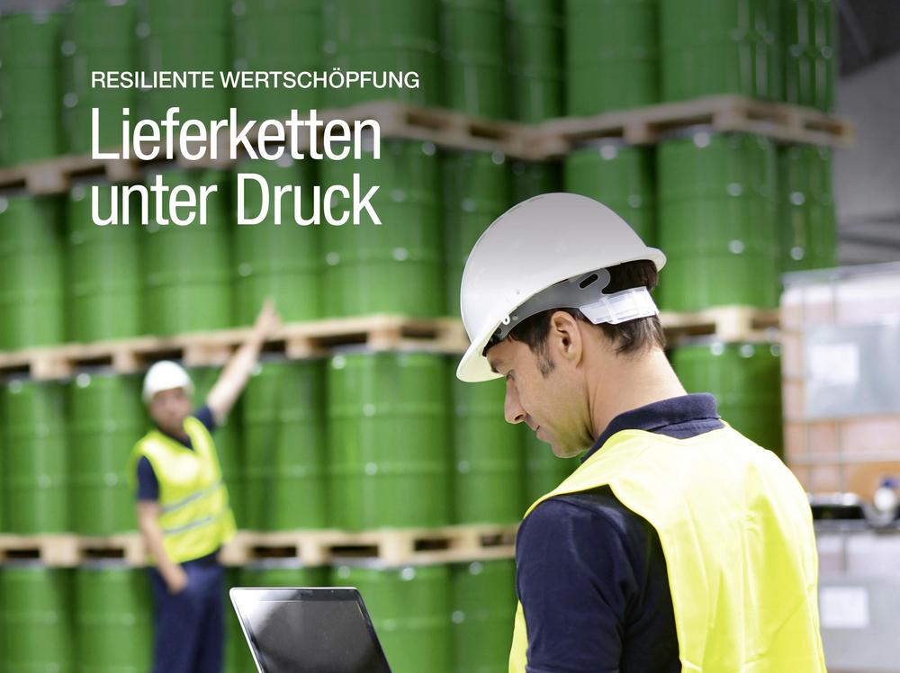 Im oberen Bereich stehen der Magazintitel, ein QR-Code sowie die Themenhinweise „Mitbestimmung: Tagung der Aufsichtsräte“, „Wirtschaftspolitik: Außenhandel mit China“ und „Recht: Interview zum Zeugnisrecht“. Das Titelmotiv zeigt eine Lager- oder Logistikhalle mit zahlreichen grünen Industriefässern, die auf Paletten gestapelt sind und den Hintergrund dominieren. Im Vordergrund steht eine Person mit weißem Schutzhelm und gelber Warnweste, die auf einem aufgeklappten Laptop arbeitet. Im Hintergrund ist eine weitere Person in Warnkleidung zu sehen, die auf die gelagerten Fässer weist. Die Aufnahme vermittelt den Eindruck einer Bestandskontrolle oder Steuerung logistischer Abläufe in einem industriellen Umfeld. Auf dem Bild steht die Schlagzeile „Resiliente Wertschöpfung: Lieferketten unter Druck“.