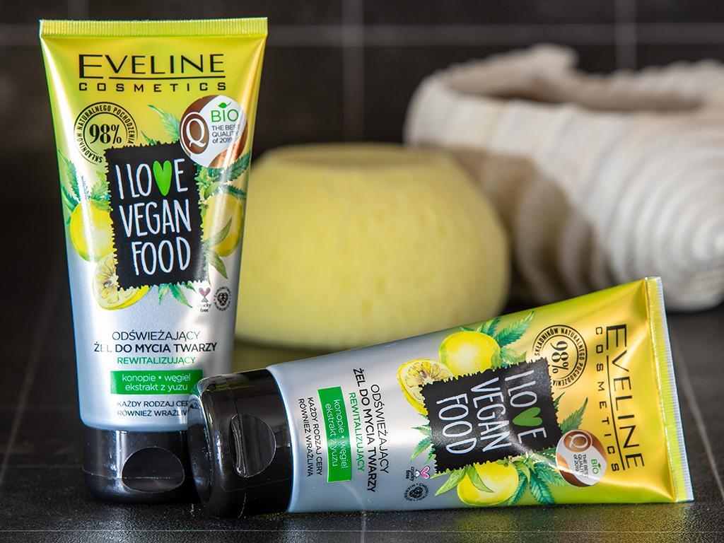 Zwei Tuben veganes Gesichtswaschgel von Eveline Cosmetics auf dunkler Oberfläche sind im Vordergrund dargestellt. Im Hintergrund sind Seife und ein gefaltetes Handtuch zu sehen.